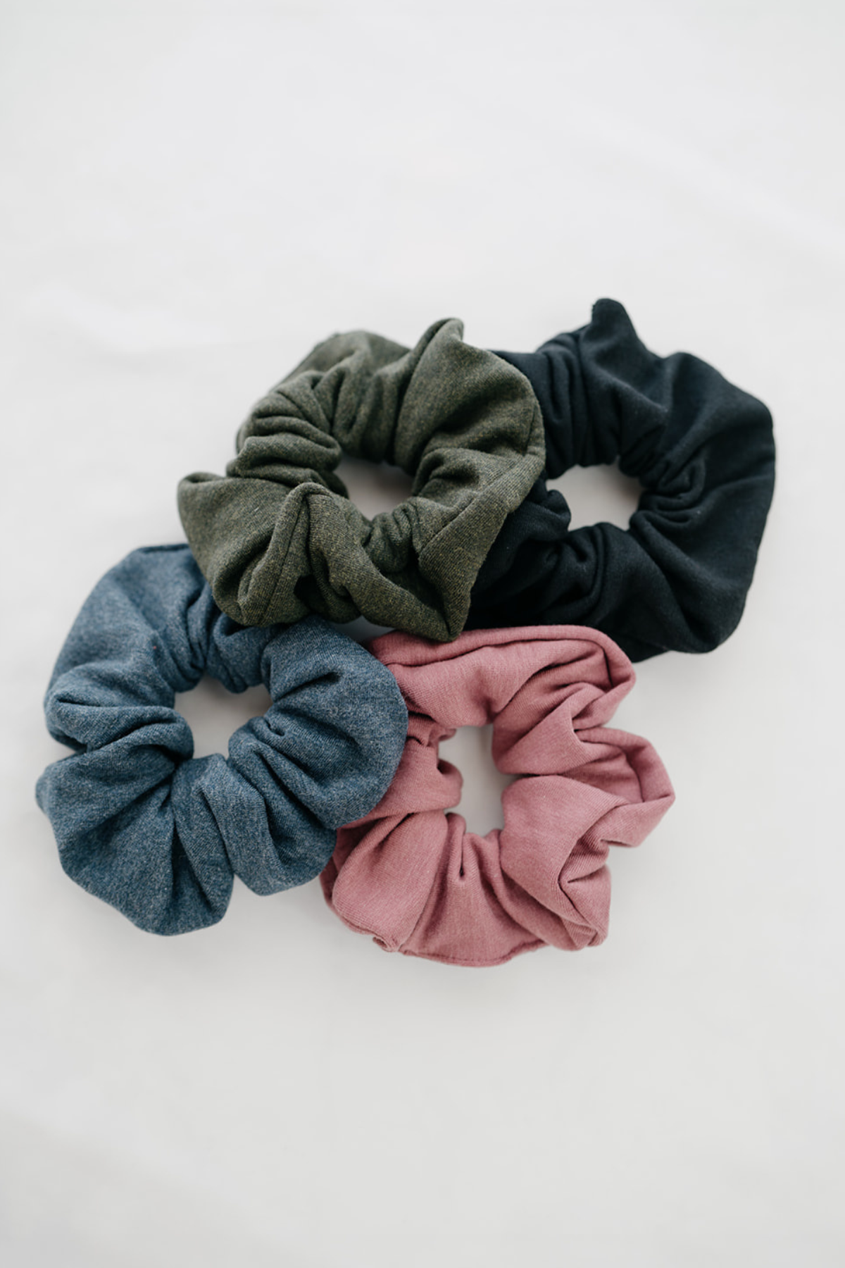 Close-up of black, pink, green and blue scrunchies on a white background