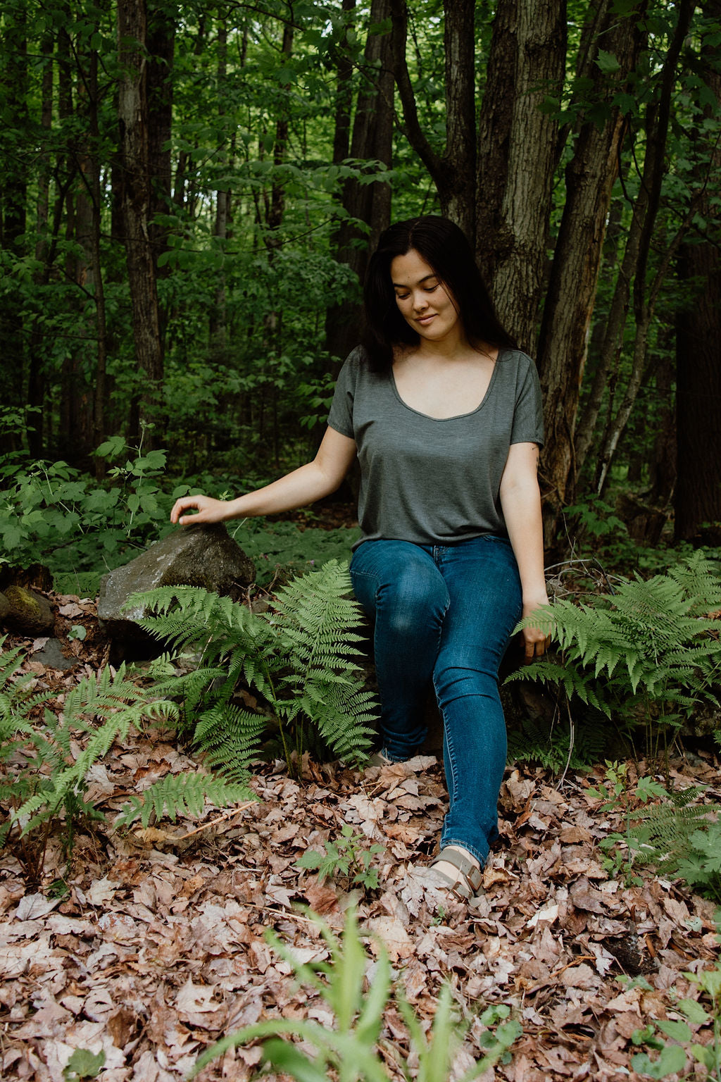Woman sitting among ferns and trees in a forest