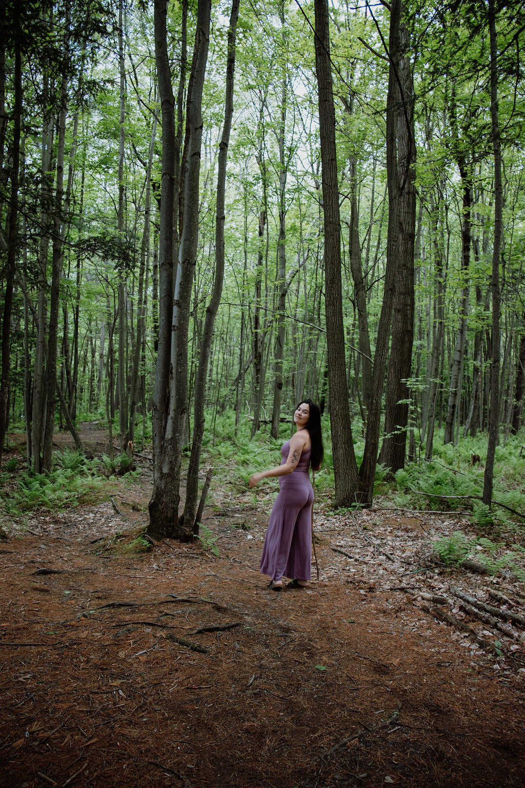 Woman in a pink crop top and palazzo pants standing in a forest