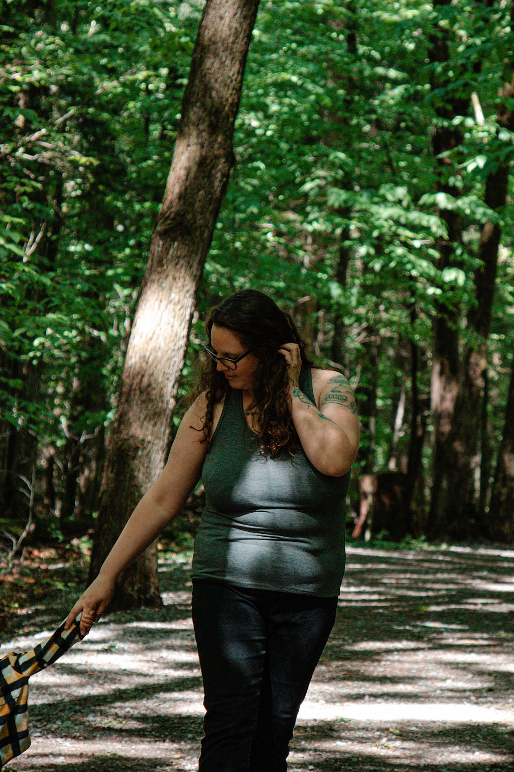 Woman walking a kidon a path in a forest wearing a grey tank top