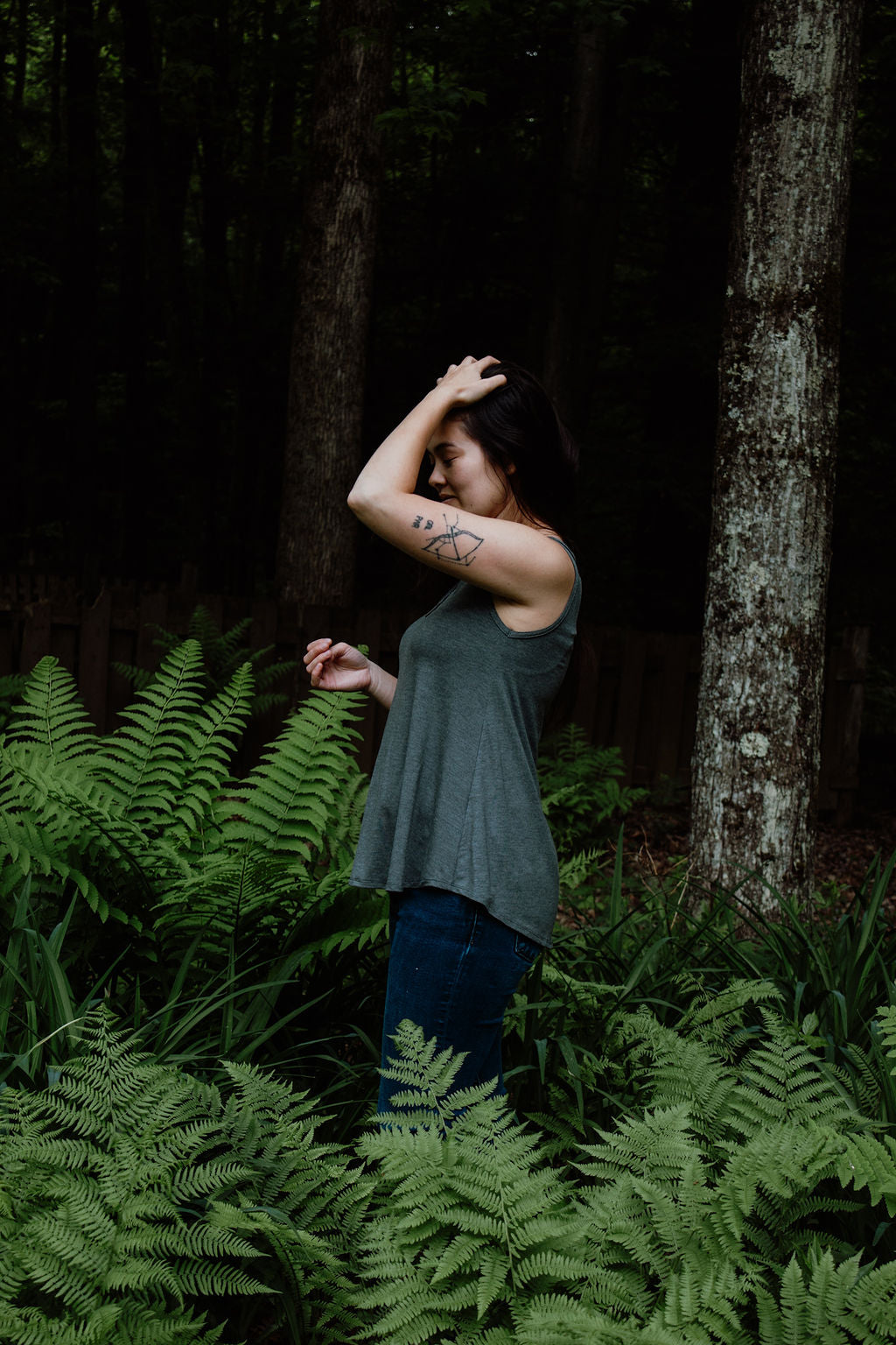 Side view of a woman wearing a gray V-neck sleeveless camisole outdoors