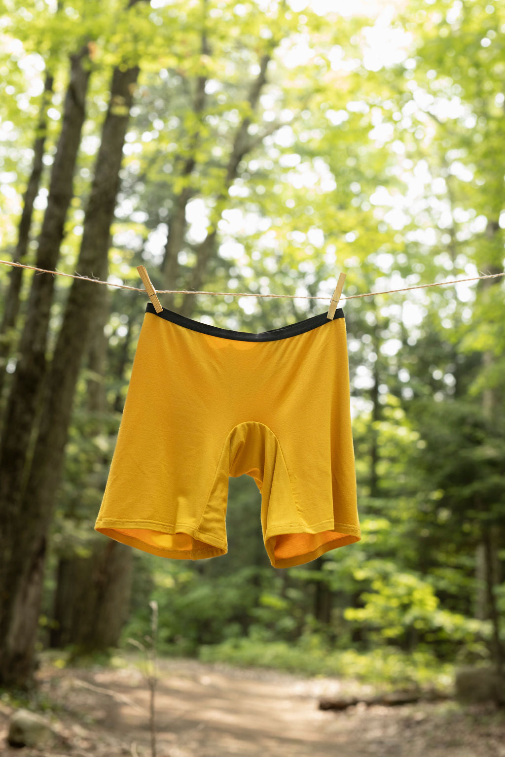 Yellow women’s bamboo boxers hanging on a clothesline outdoors in a forest