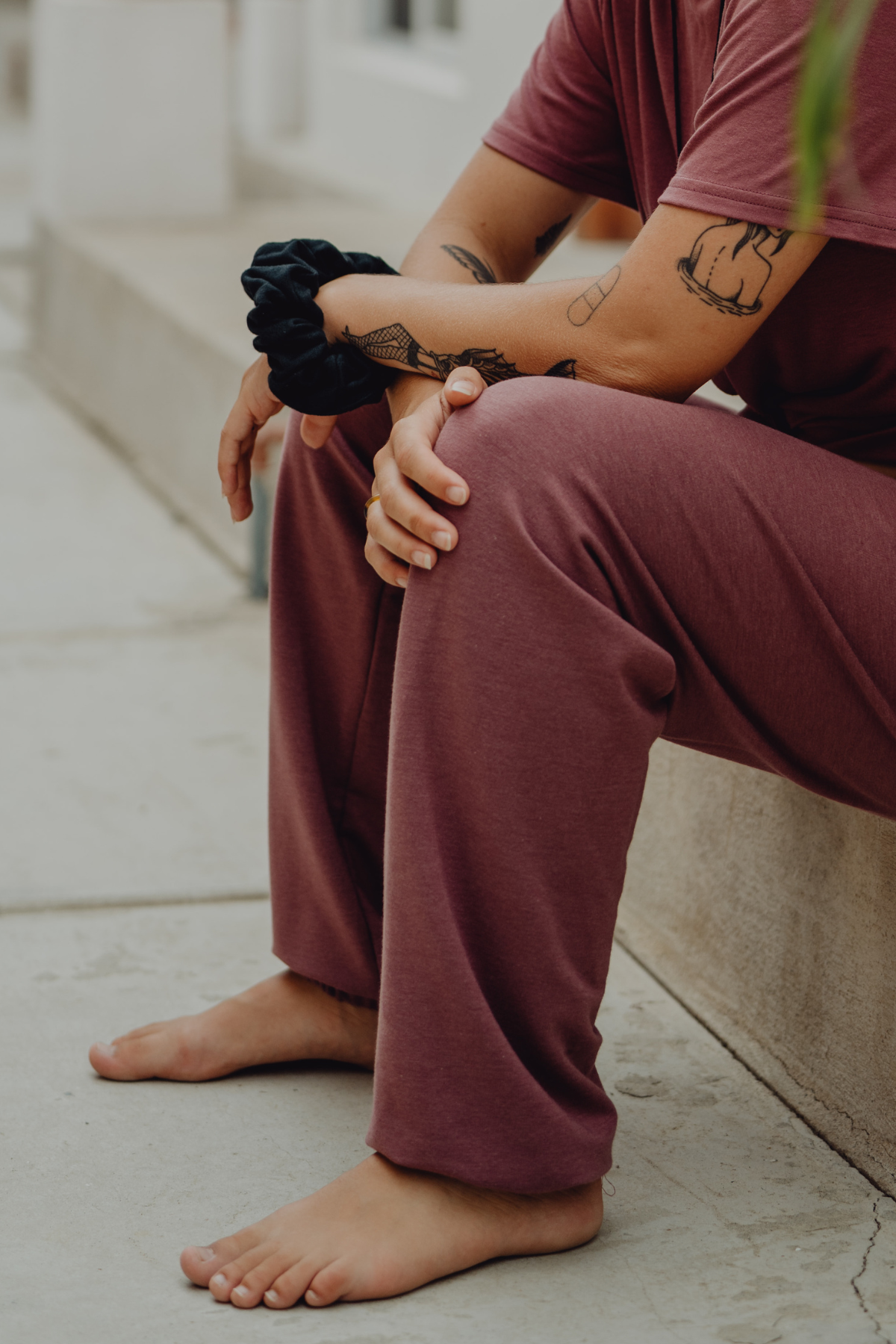 A woman wearing pink joggers with a black hair scrunchie on her wrist