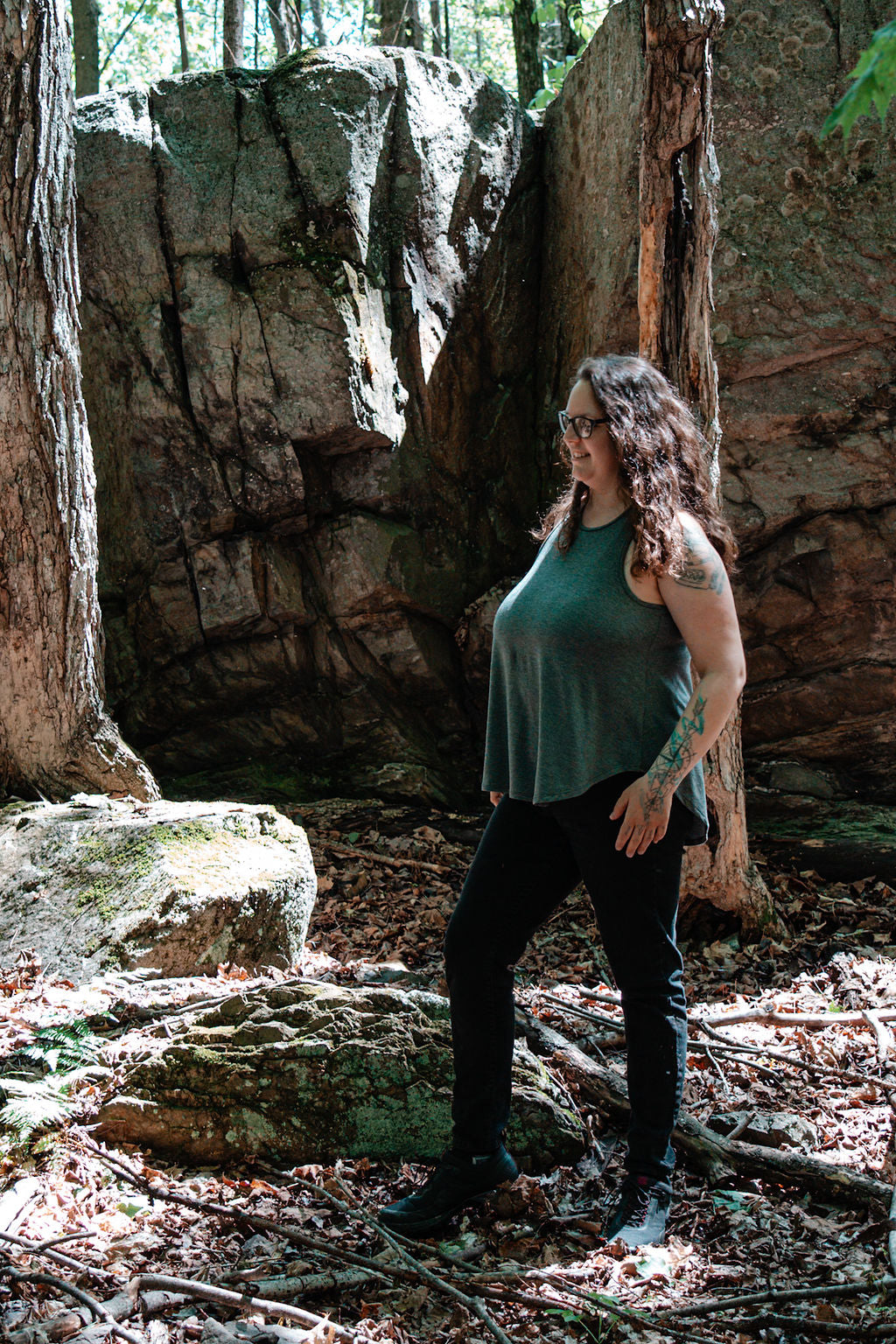 Woman standing in a forest with large rocks and trees