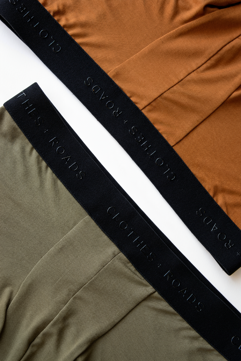 Black elastic with 'Clothes + Roads' branding on an orange and green fabric background