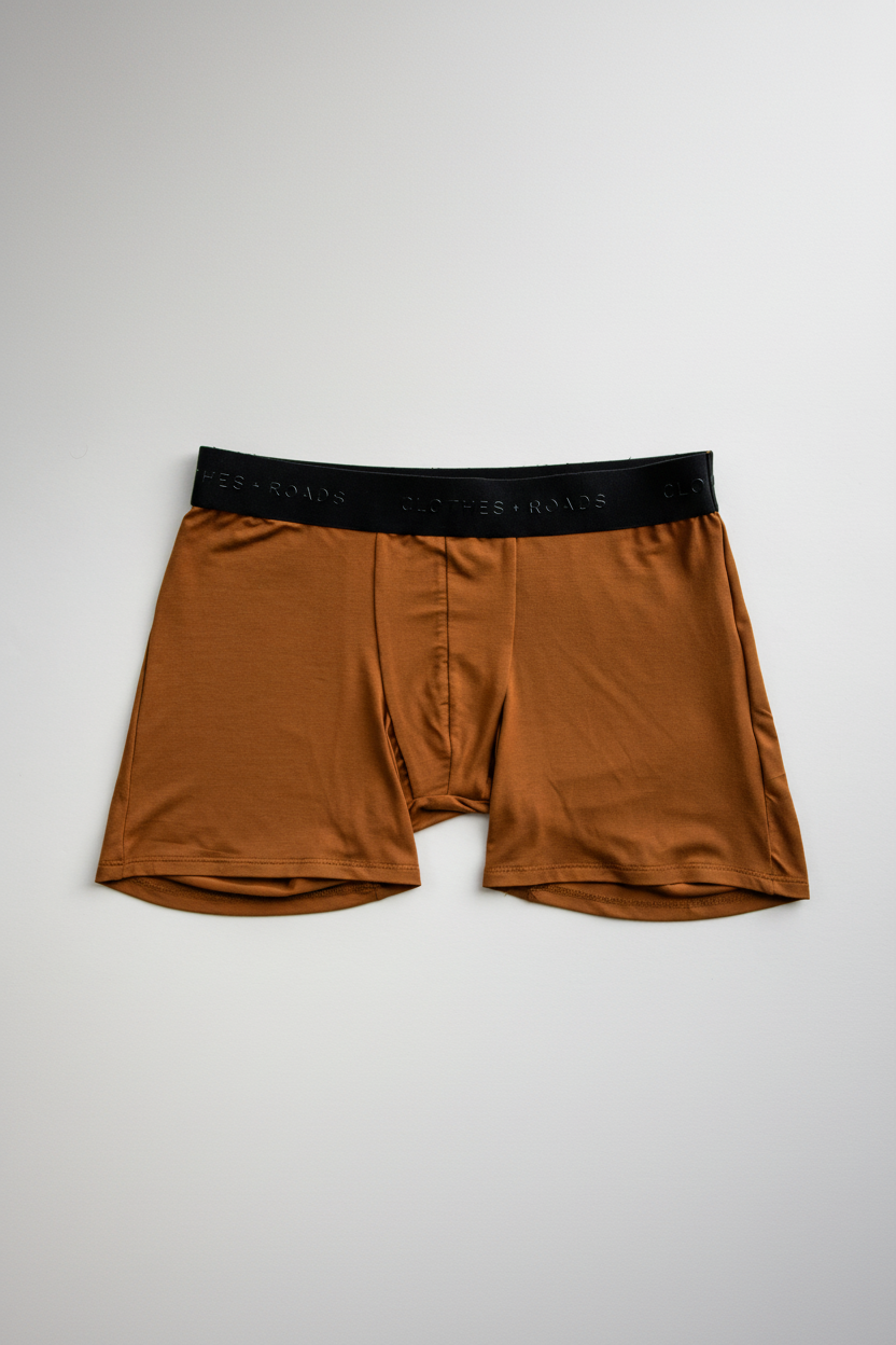 Orange boxer briefs with black waistband on a light gray background