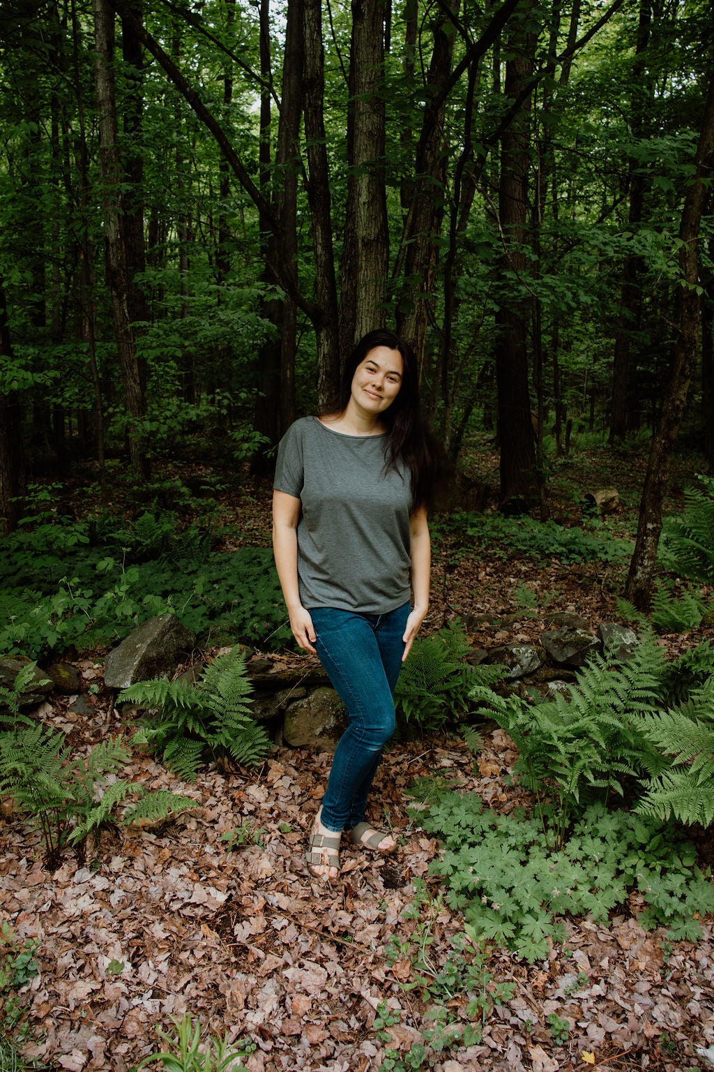 Woman standing in a forest with greenery around her