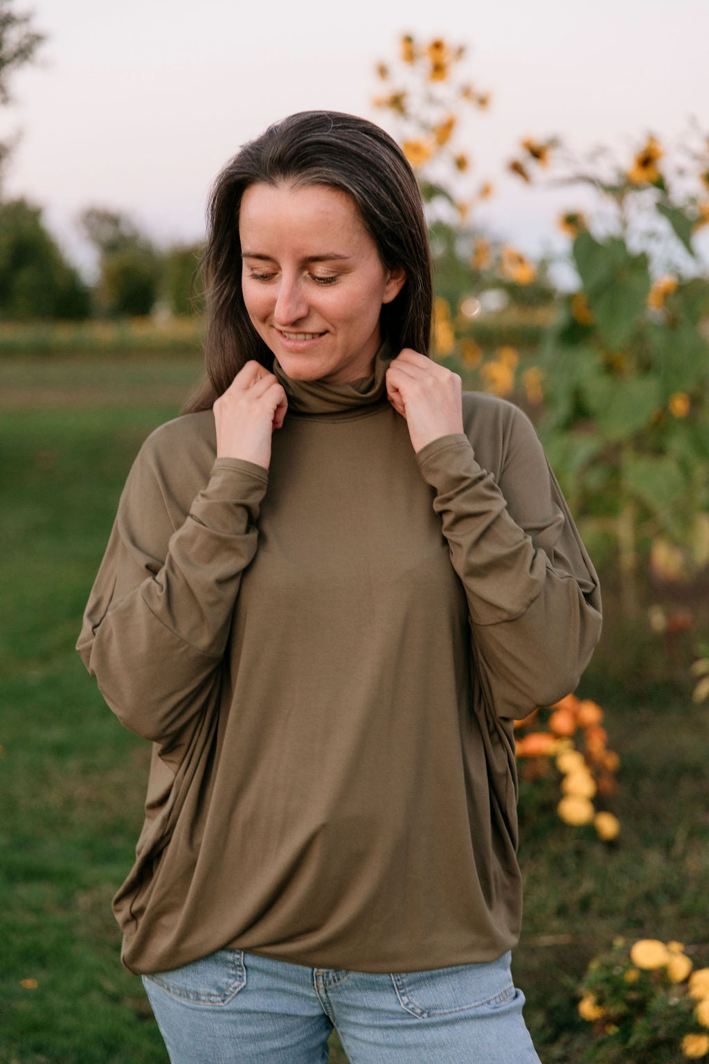 Woman wearing an olive long-sleeve top in a sunflower field