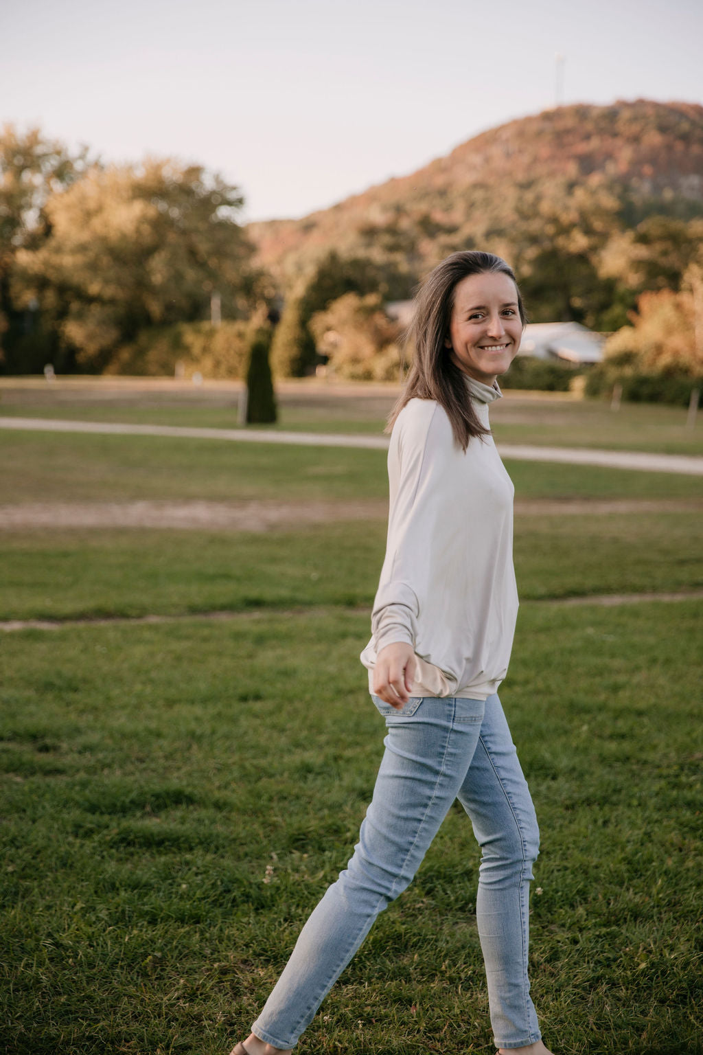 Woman wearing The Batwing Long-Sleeve Top in Taupe, standing outdoors with trees in the background.