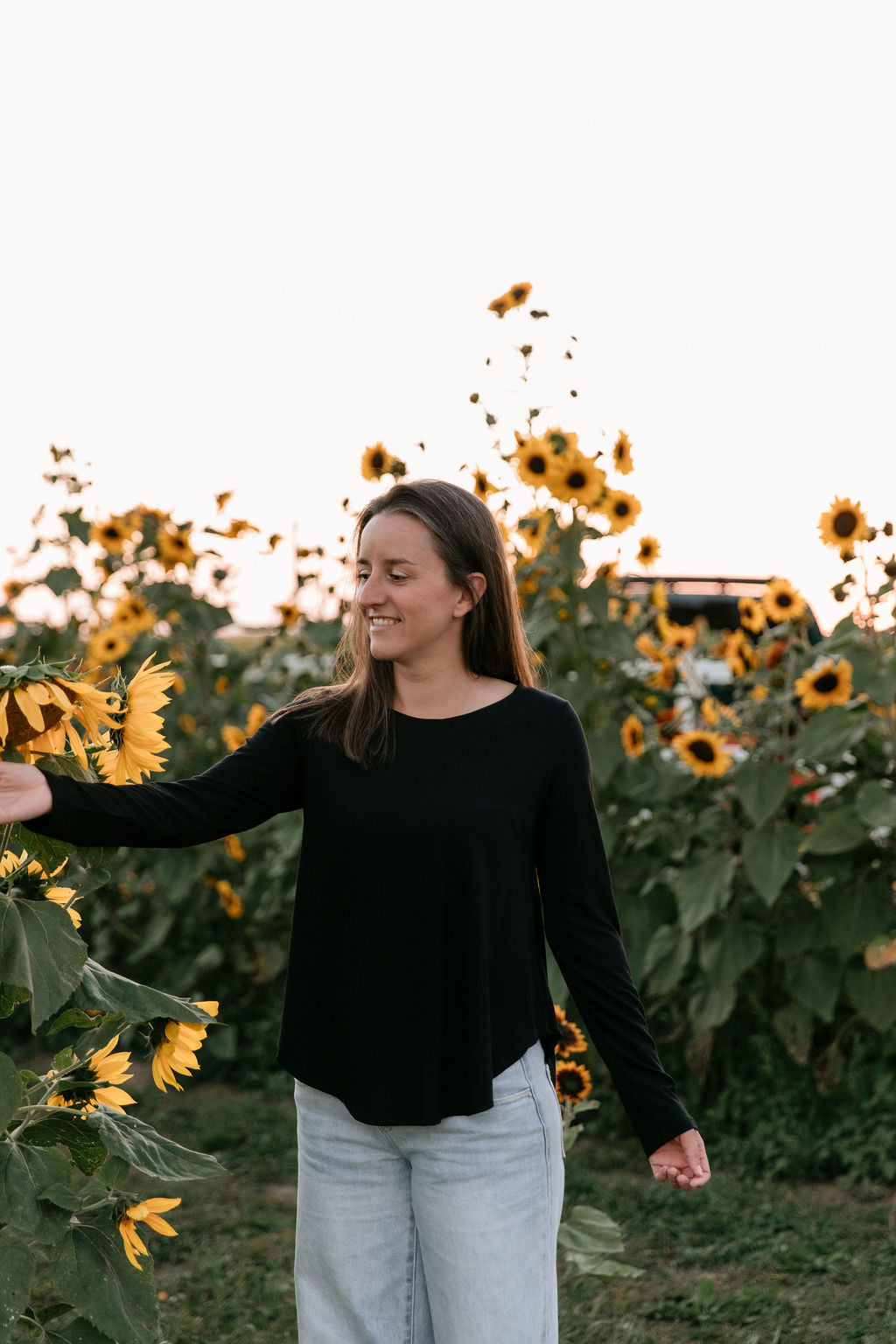 Woman wearing The Breezy Long-Sleeve Shirt in Black, standing in a sunflower field.