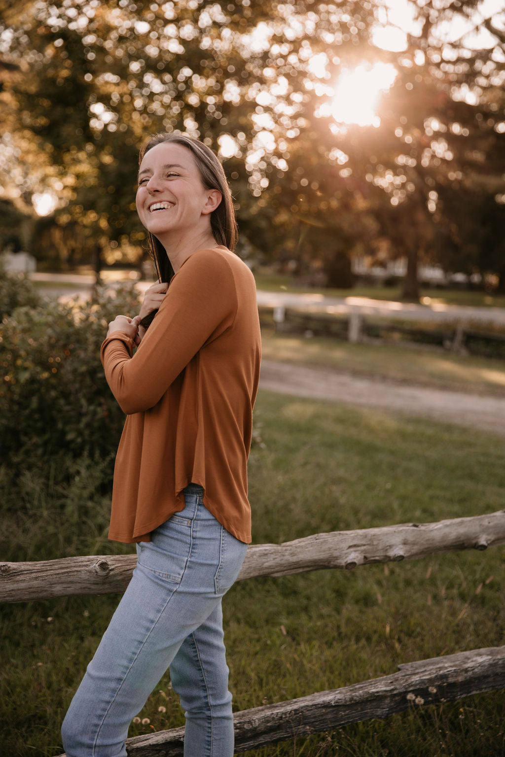Woman wearing The Breezy Long-Sleeve Shirt in Redwood and light blue jeans.