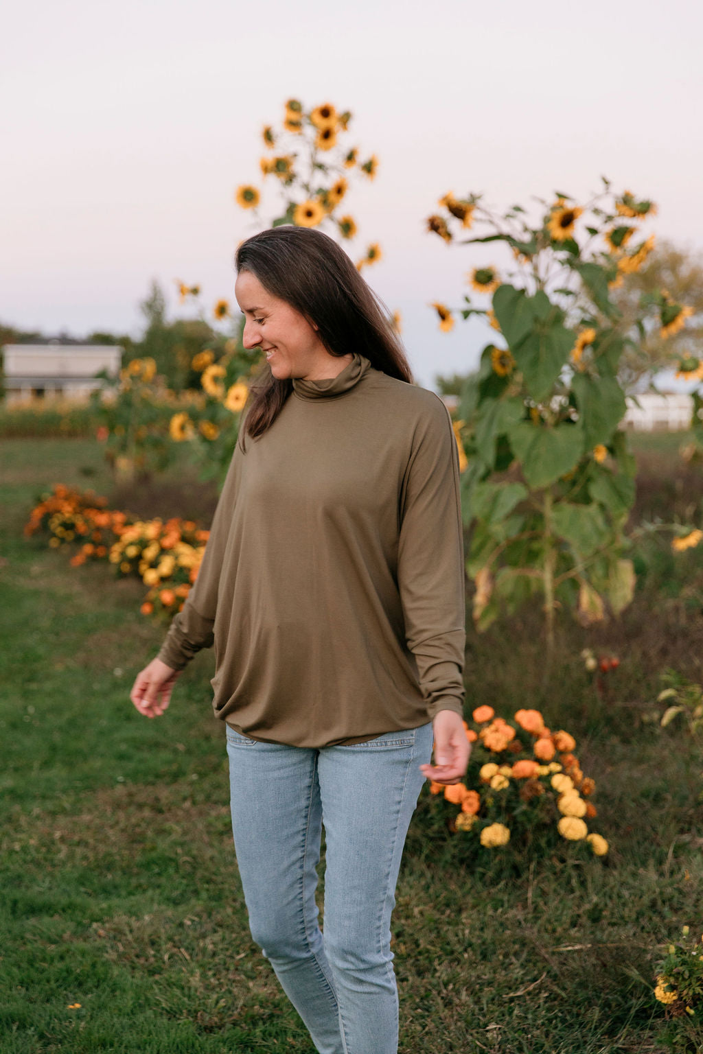 Woman wearing The Batwing Long-Sleeve Top in Olive in a sunflower field.