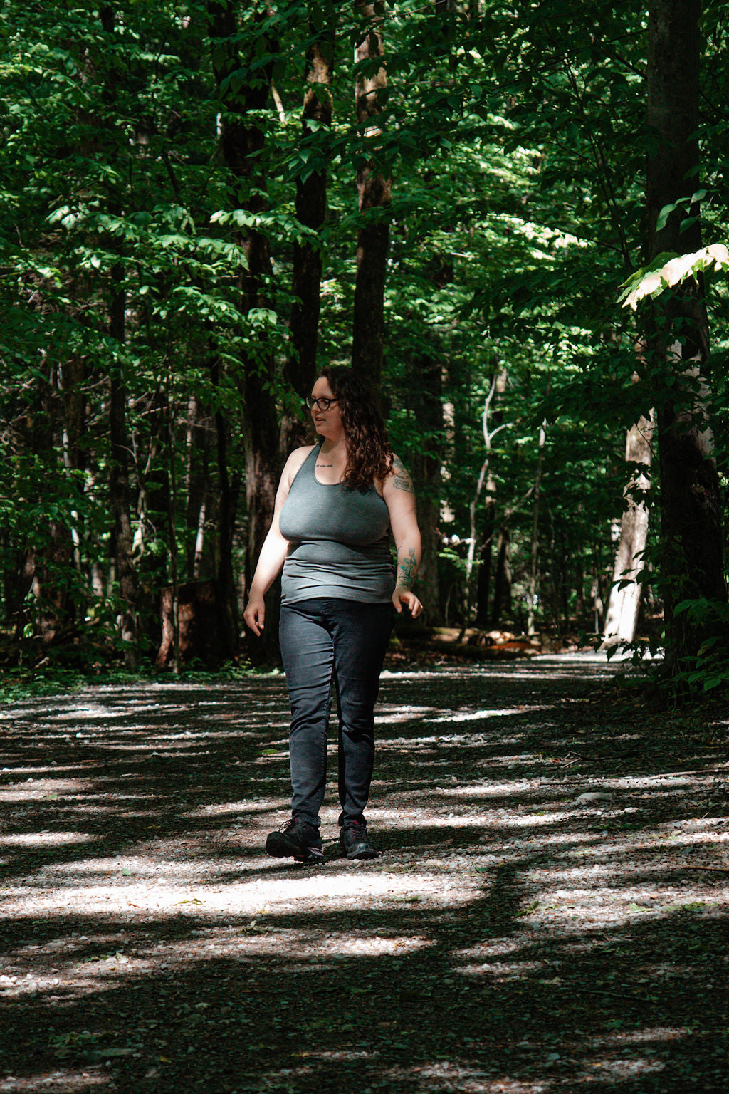 Person walking on a forest path with sunlight filtering through the trees
