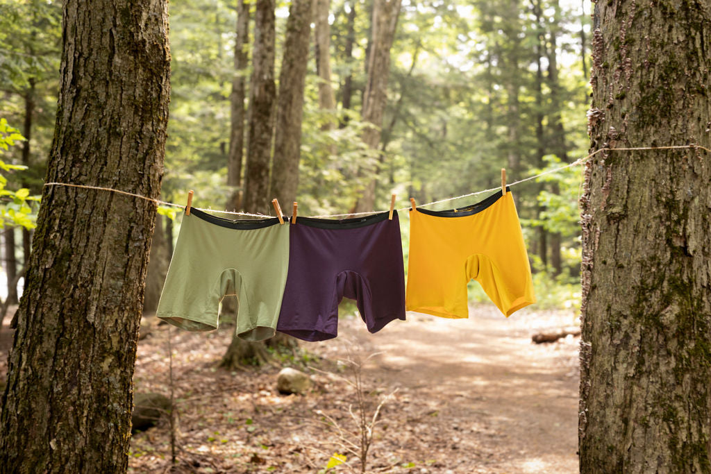 Three pairs of women’s long bamboo boxer underwear hanging on a clothesline in a forest