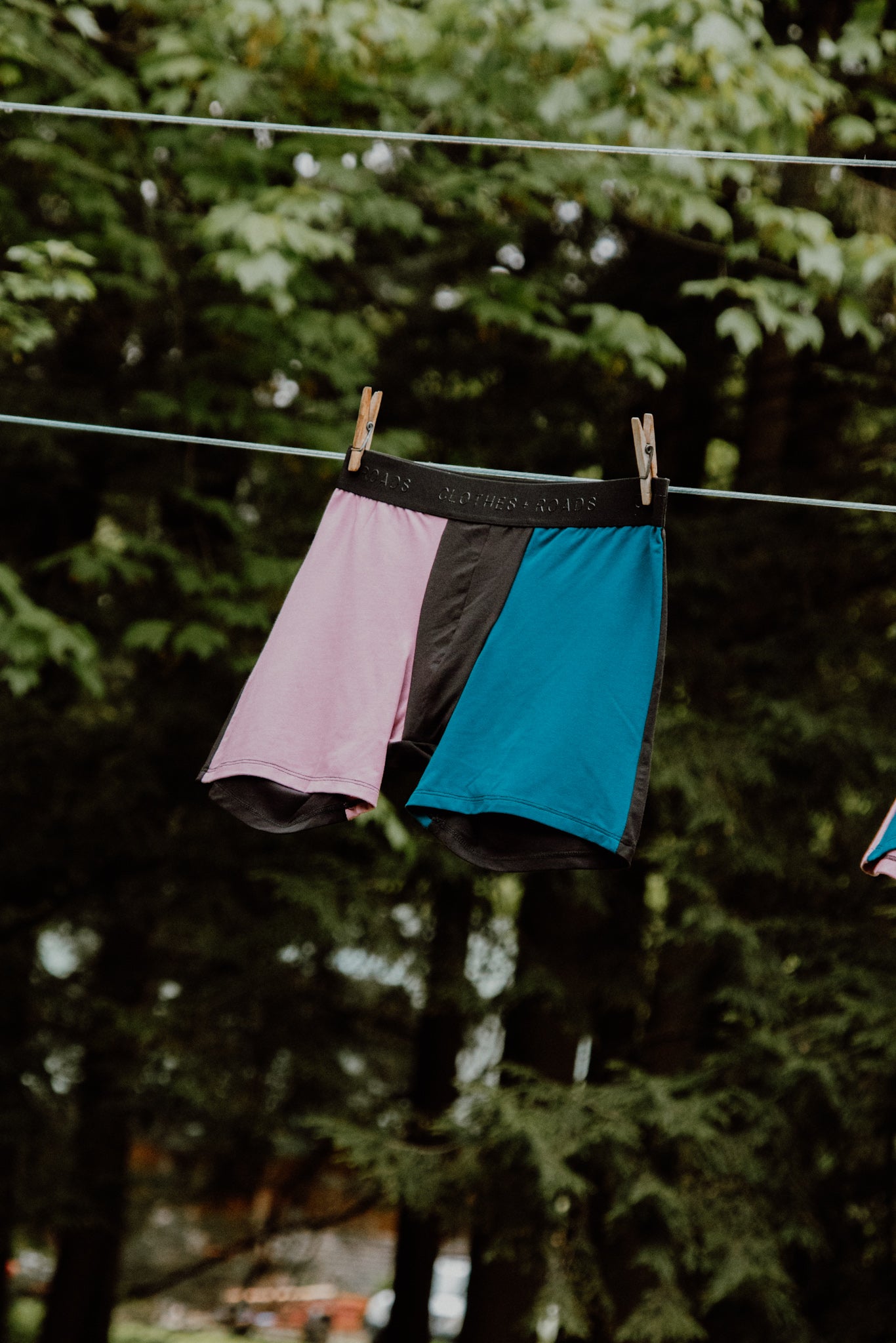 Close-up of men’s boxer briefs hanging on a clothesline with trees in the background.