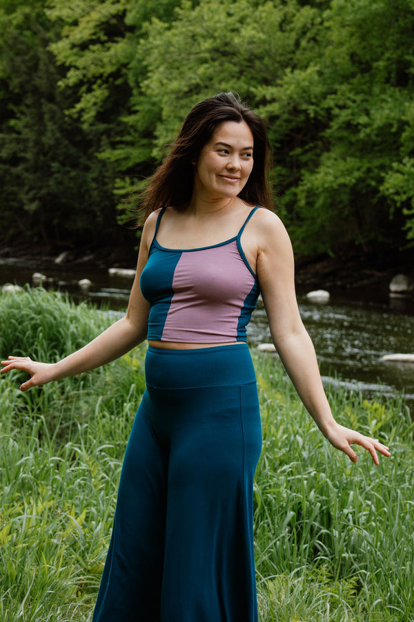 Woman wearing a zero-waste crop top in teal and dusty rose with teal Palazzo pants, front view.