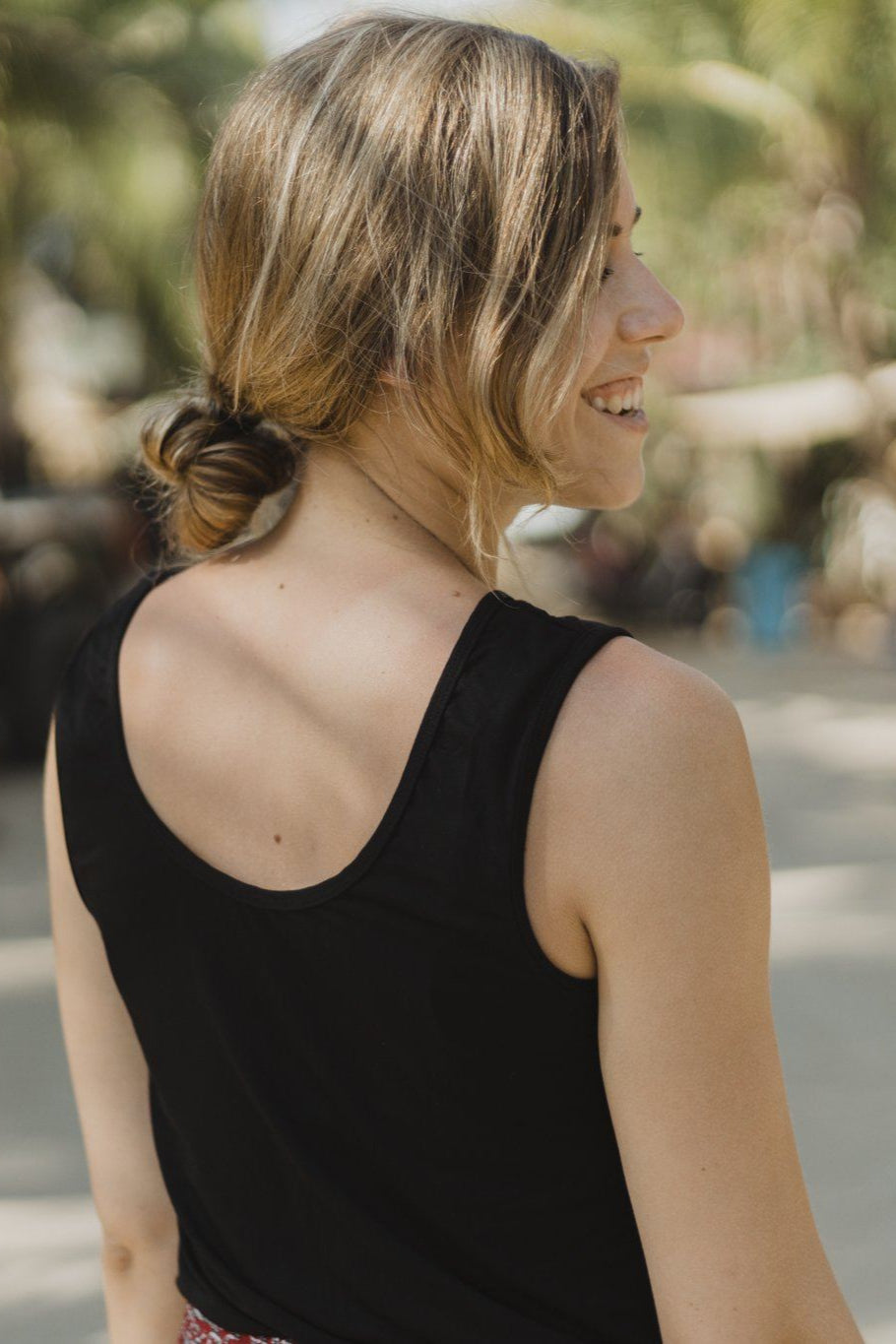 Back view with scoopneck of the black reversible bamboo camisole worn by a woman.