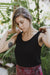 Close-up of a woman wearing the black reversible bamboo camisole, front view with scoopneck.
